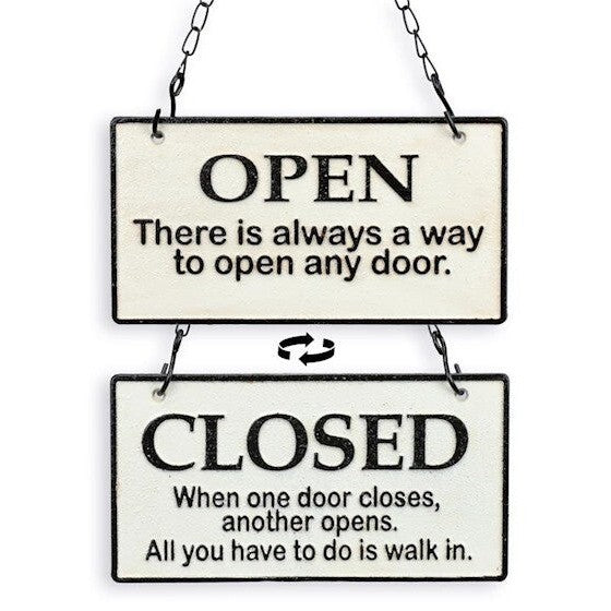 Double-sided handcrafted iron Open and Closed hanging sign with humorous text suspended by black metal chains.
