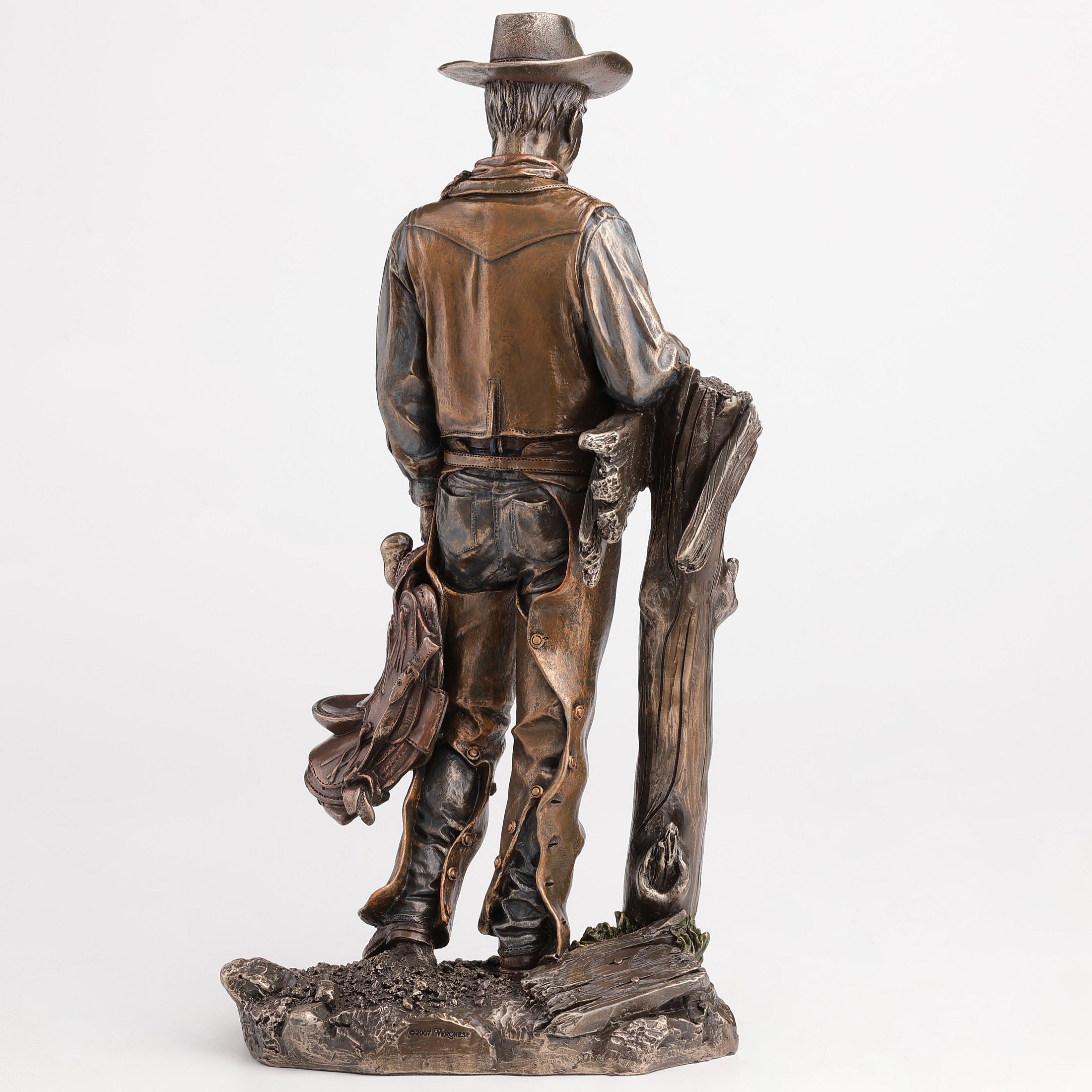 Cowboy Holding Saddle Leaning Against Fence Pole