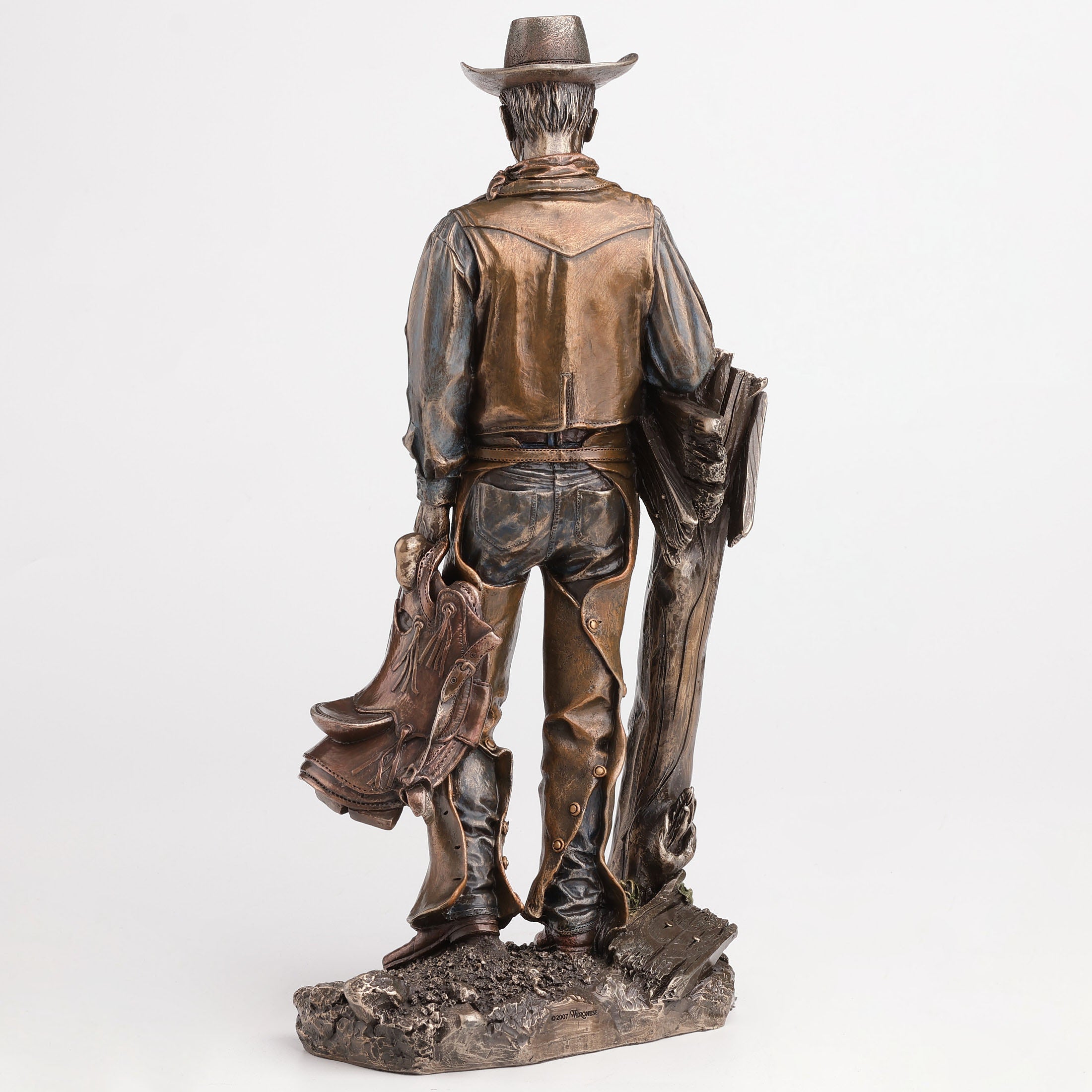 Cowboy Holding Saddle Leaning Against Fence Pole