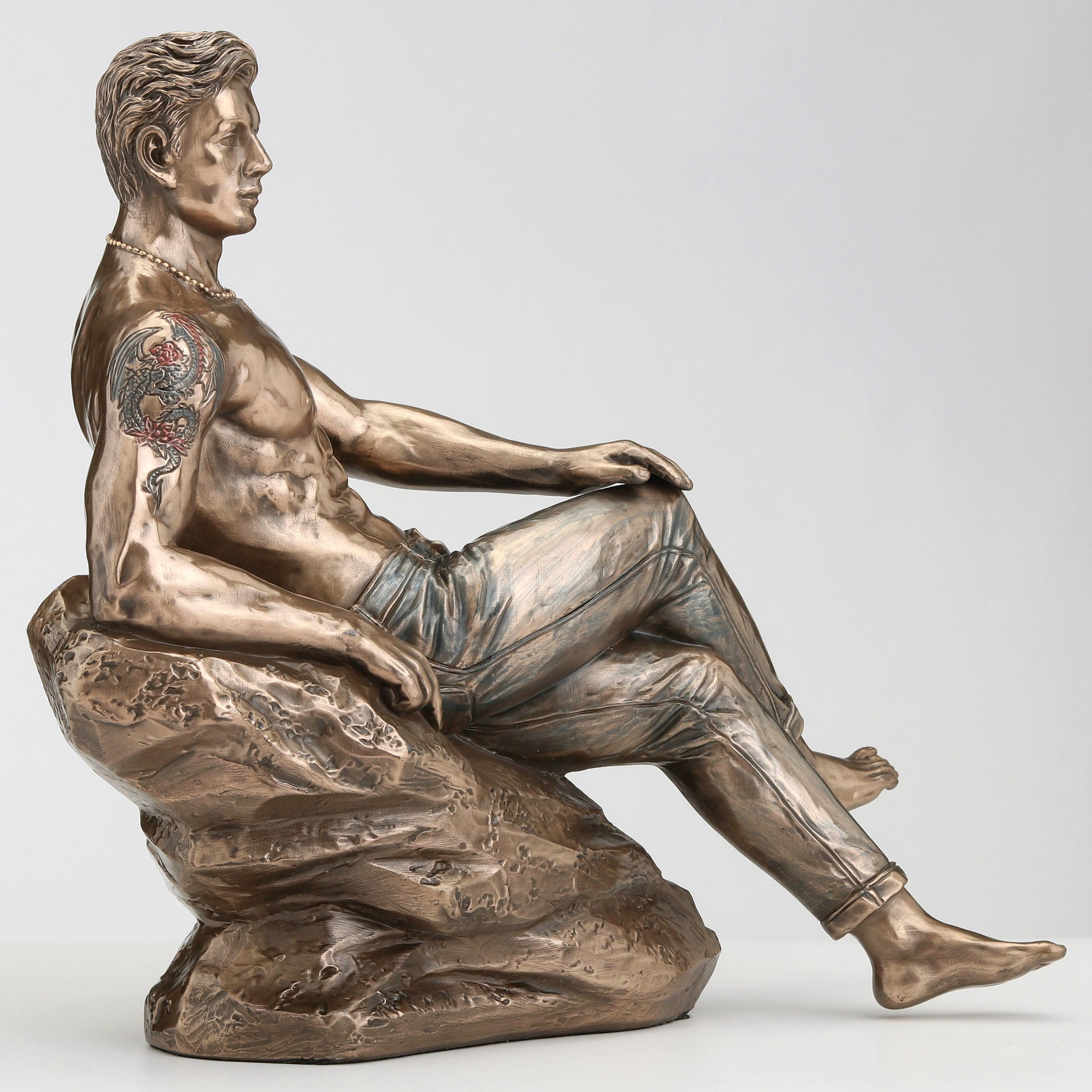 Tattooed Male In Jeans Pin Up Crossed Legs Lean On Rock
